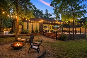 Ein moderner Außenbereich mit Terrasse, Feuerstelle, Sitzgelegenheiten und Lichterketten.