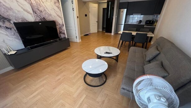 Una sala de estar moderna con un televisor de pantalla plana, un sofá, una mesa de comedor y un ventilador.