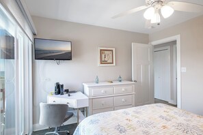 A bedroom with a bed, a desk, a chair, a television, and a door. - Pebble Beach D-206 3BR Oceanfront Condo (Emeral Isle)