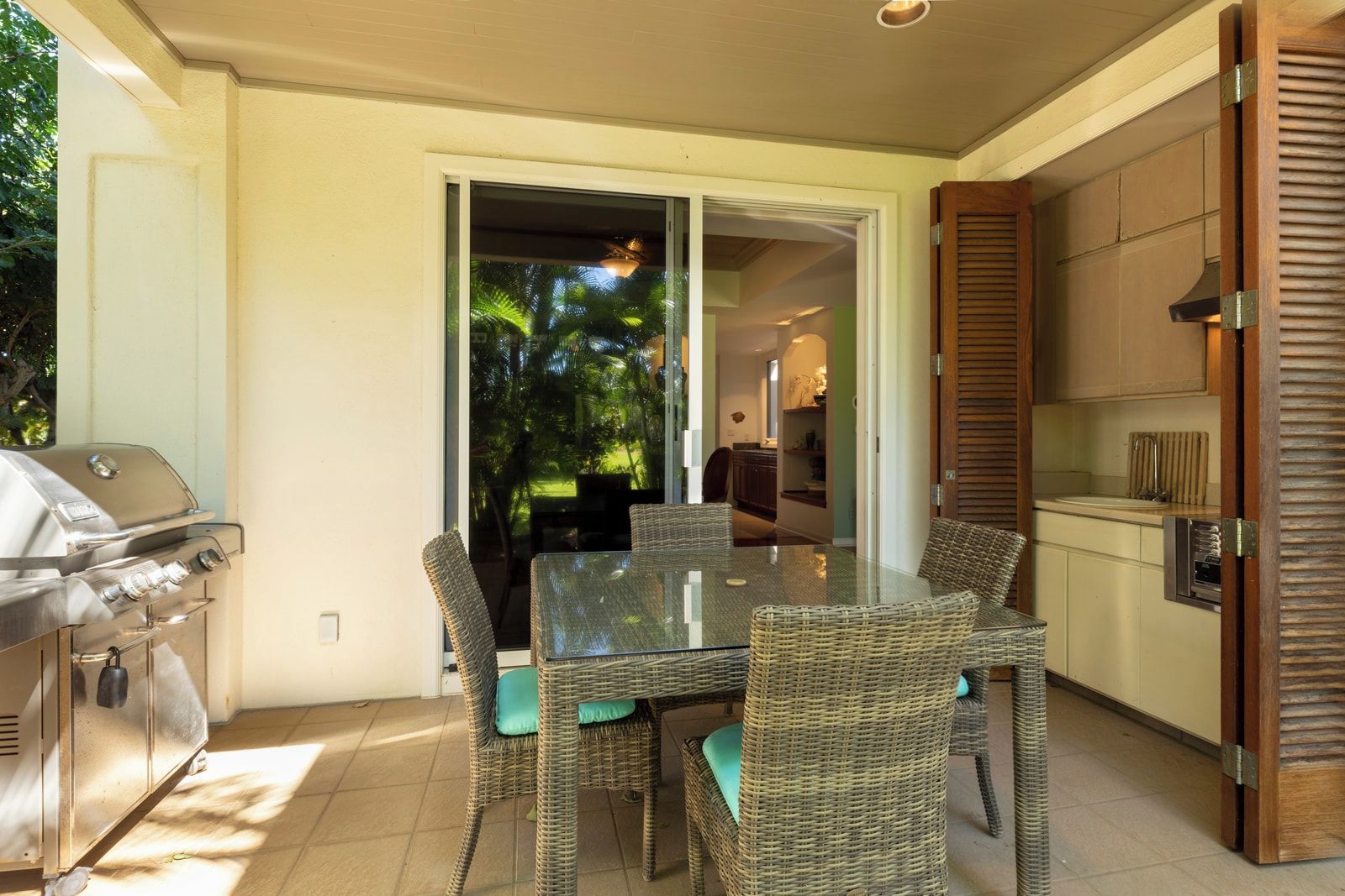 A patio with a grill, wicker furniture, and a view of the outdoors.