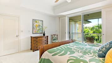 Een slaapkamer met een bed, een dressoir, een schilderij en een balkon met tuinmeubilair.