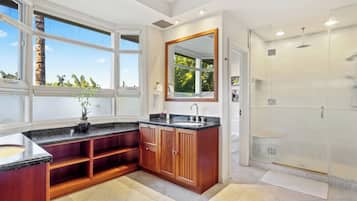 Una cucina moderna con un'ampia finestra, lavello integrato, mobili in legno e cabina doccia in vetro.
