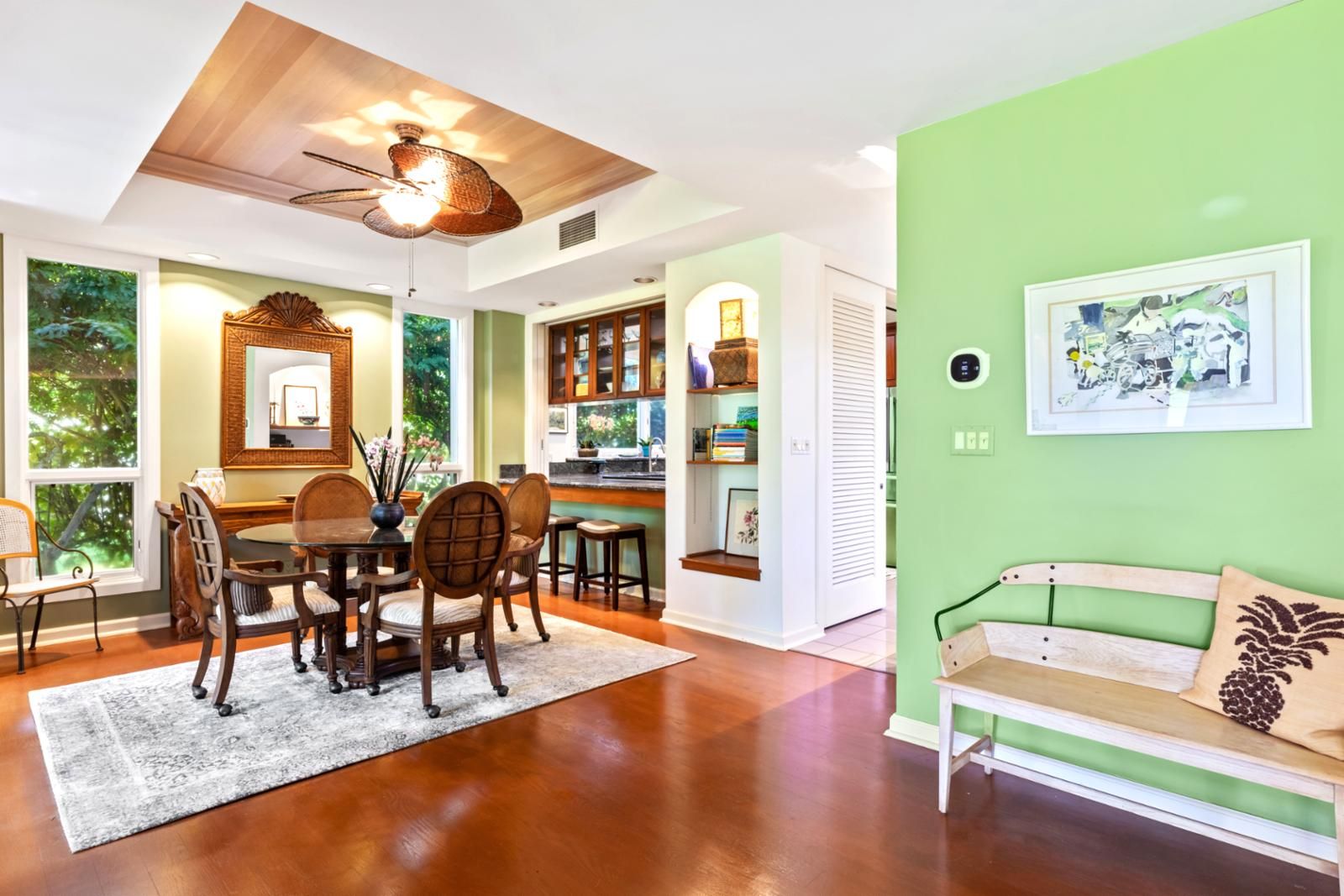 A dining area with a wooden table and chairs, a ceiling fan, and a view of the outdoors.