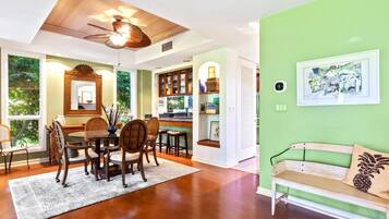 A dining area with a wooden table and chairs, a ceiling fan, and a view of the outdoors.