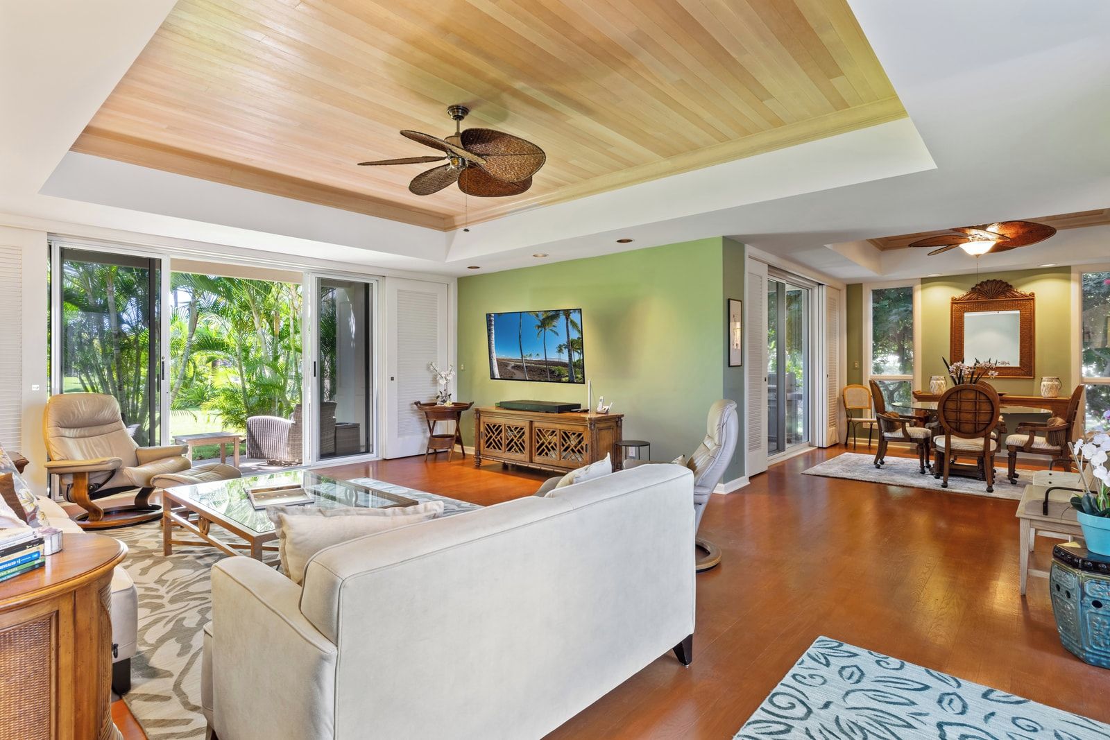 A spacious living area with a ceiling fan, a television, and a dining area with chairs and a table.