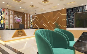 Zona de recepción de hotel con un diseño moderno, que incluye un letrero de neón, un mostrador de recepción y disposiciones para sentarse.