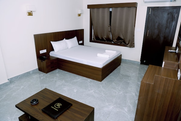 Habitación de hotel con cama, mesita de noche y escritorio.