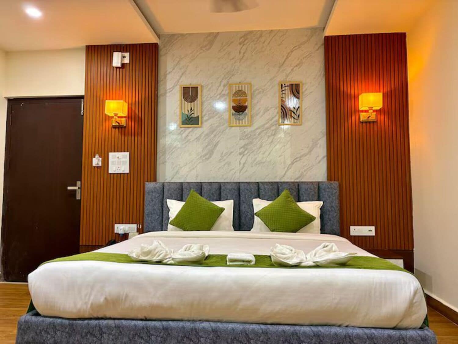 Une chambre d’hôtel avec un lit, des murs recouverts de panneaux en bois, un mur en marbre et des lampes fixées au mur.