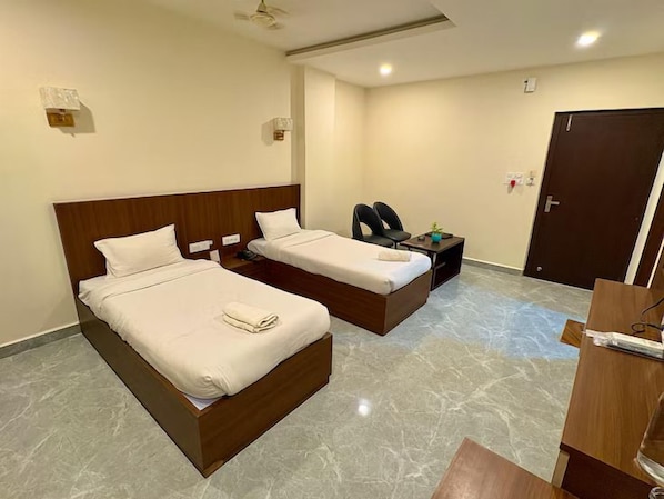 Habitación de hotel con dos camas, un escritorio, una silla y una puerta.