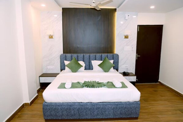 Una habitación de hotel moderna con una cama grande, un ventilador de techo y una puerta de madera oscura.