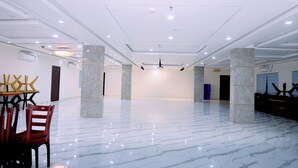 Un amplio espacio interior con piso de mármol pulido, paredes blancas e iluminación empotrada en el techo.