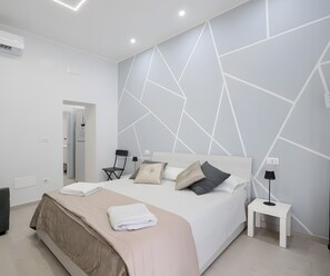 Une chambre à coucher moderne avec un lit, des tables de chevet et un motif géométrique sur le mur.