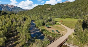 A river running through a forested area with a bridge and a small structure with a green roof.