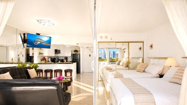 Ein modernes Hotelzimmer mit Sofa, Bett, Küchenzeile und Fernseher.