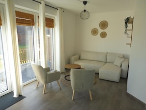 A living room with a sofa, two chairs, a coffee table, and a hanging light fixture.