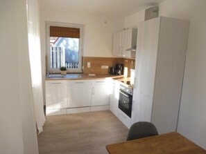 A compact kitchen with white cabinets, a wooden countertop, a sink, and a stove.