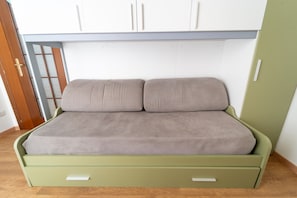 A green bed with two pillows and a wooden floor. - Appartamento in Piazzetta by Wonderful Italy (Naples)