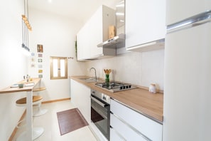 A modern kitchen with a gas stove, stainless steel appliances, and a wooden countertop. - Appartamento in Piazzetta by Wonderful Italy (Naples)