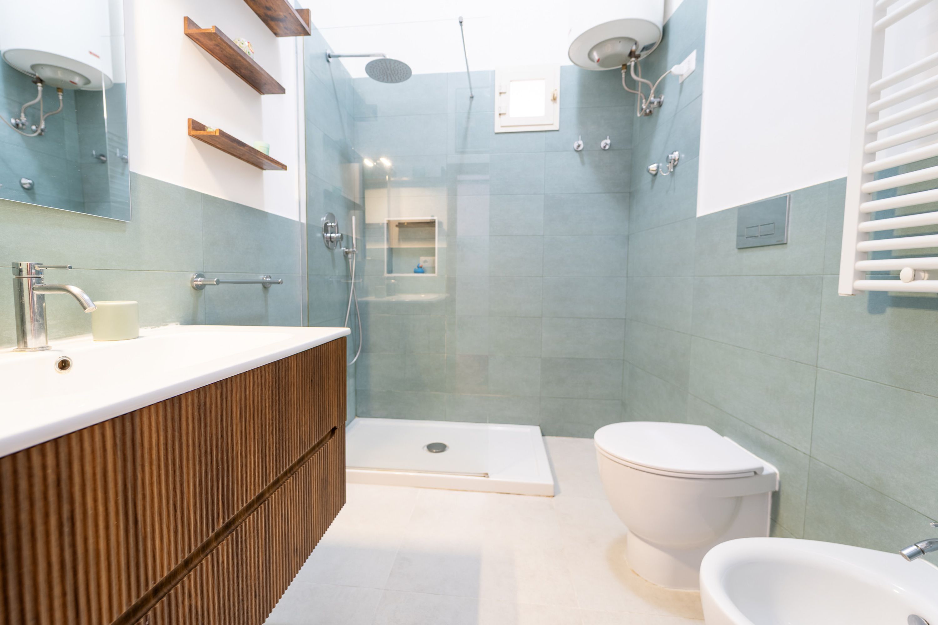 A modern bathroom with a wooden vanity, a white toilet, and a glass-enclosed shower area.