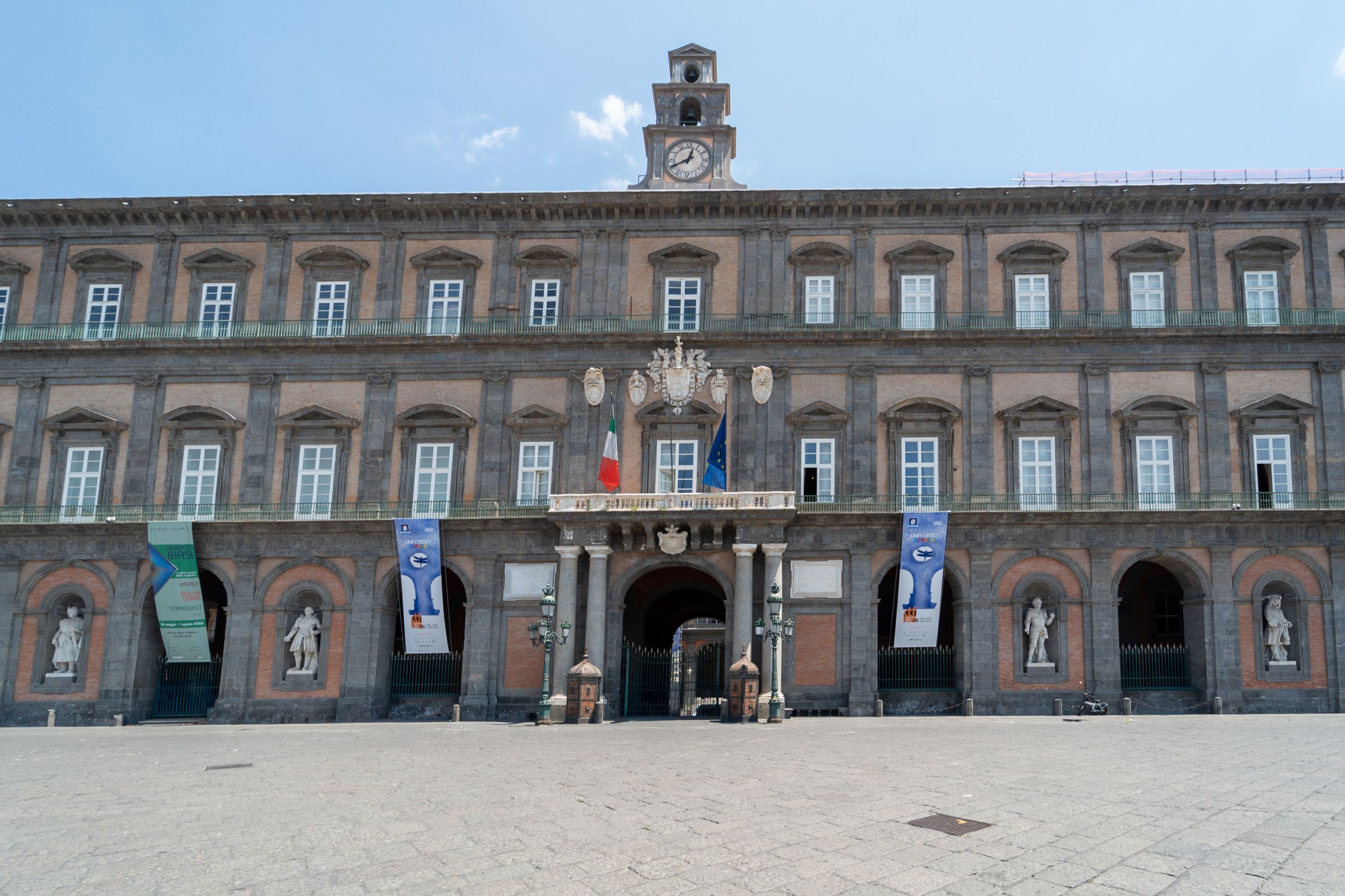 A historic building with a central entrance, statues, and flags.