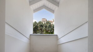 Un balcone stretto con pareti bianche e una griglia metallica alla base.
