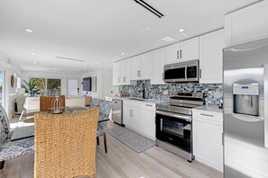 A modern kitchen with white cabinets, stainless steel appliances, and a tiled backsplash.