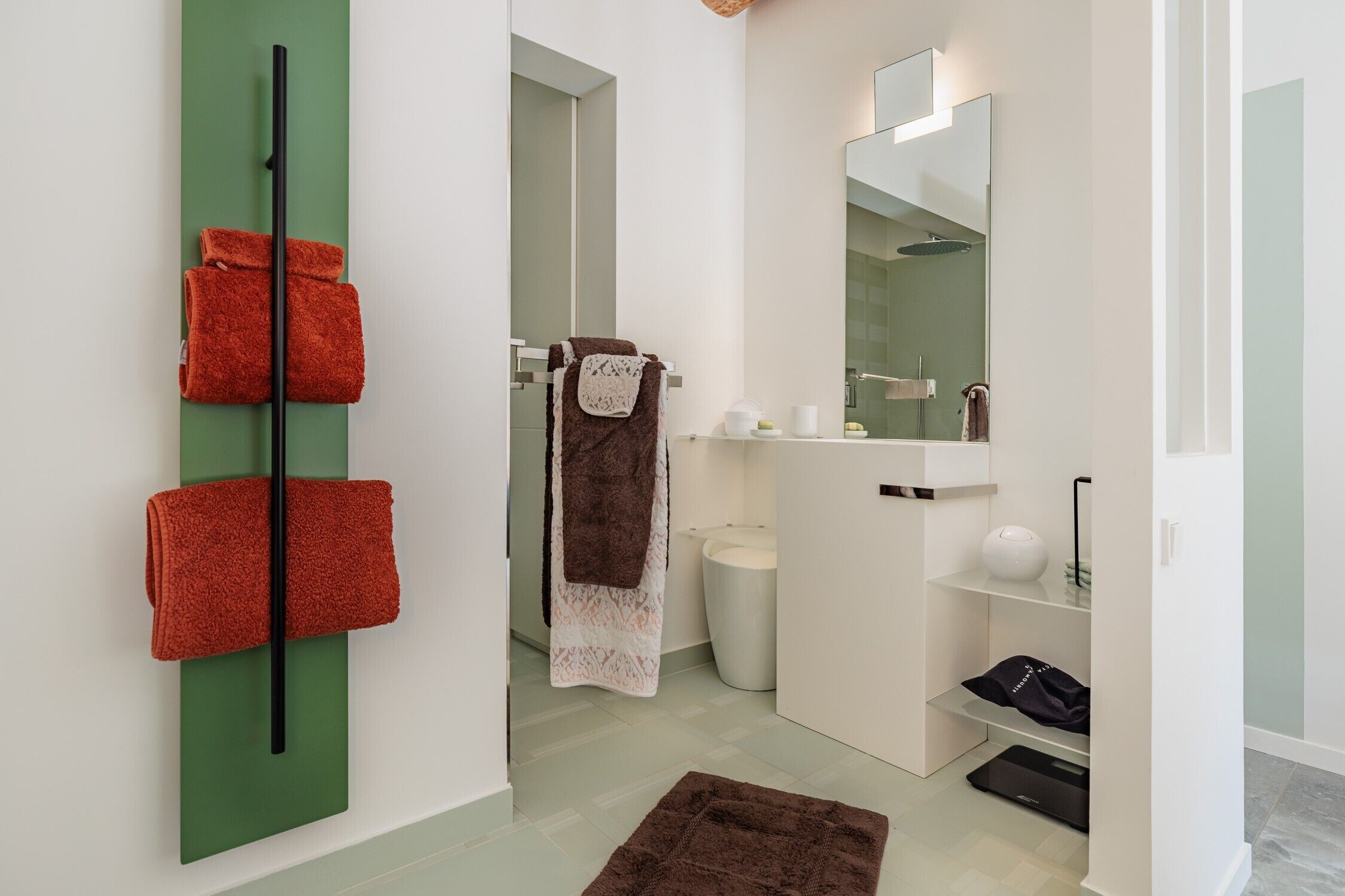 Un baño moderno con un toallero verde, un lavabo blanco y un espejo.