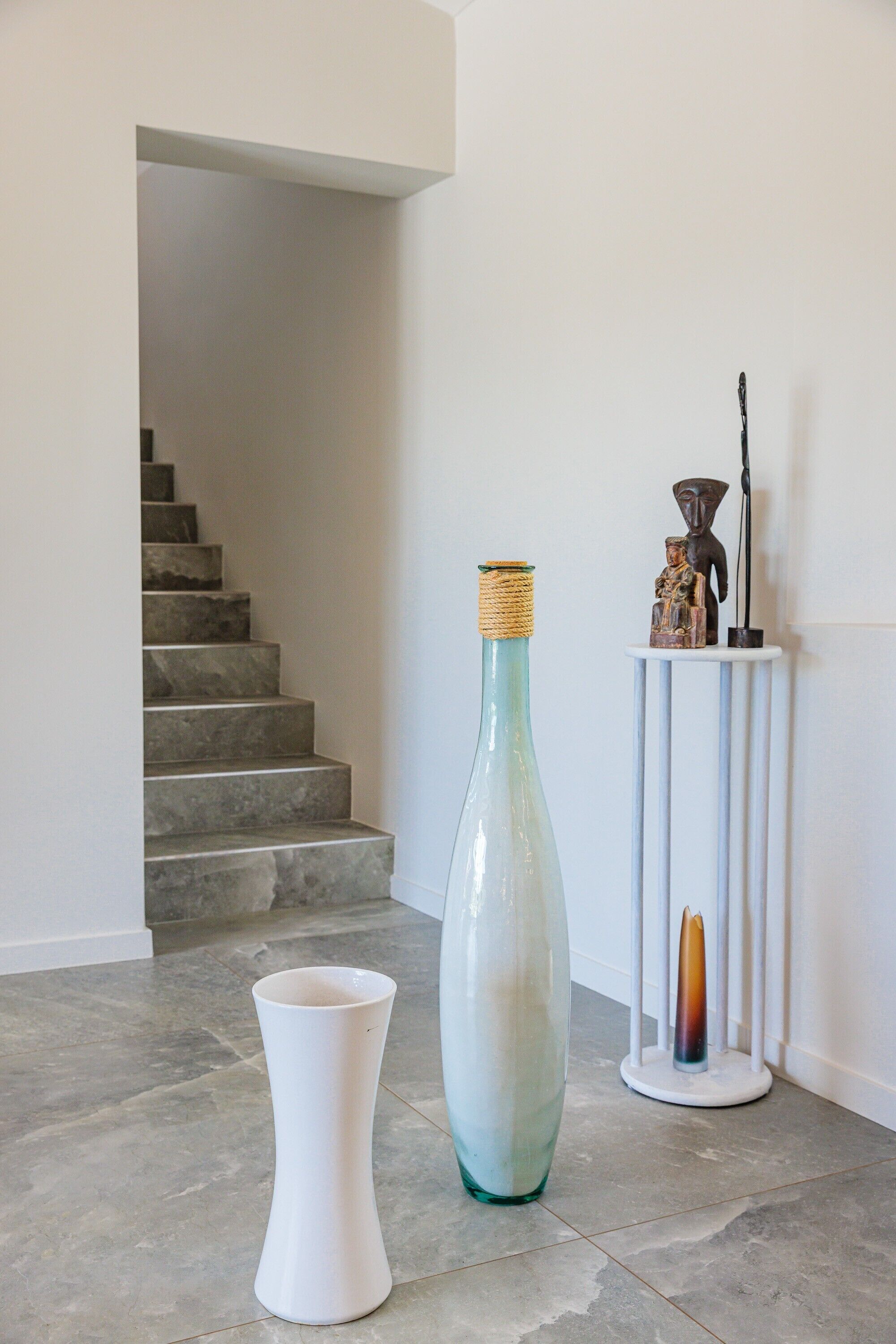 Una escalera lleva a un rellano con una pared blanca y una pequeña mesa blanca decorada.