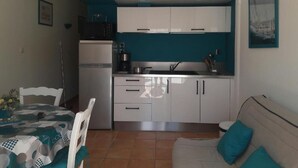 Una cocina compacta con armarios blancos, horno integrado y cafetera.