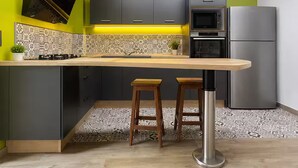 Een moderne keuken met een centraal eiland, barstoelen, een magnetron en een koelkast.