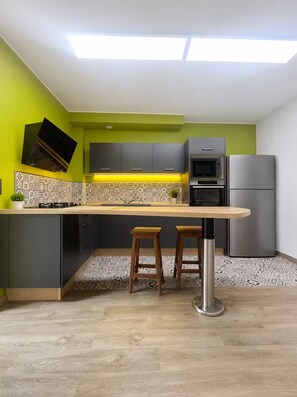 Eine moderne Küche mit Kochinsel, Barhocker, einer Mikrowelle und einem Kühlschrank.