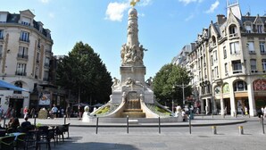 Een openbaar plein met een centraal monument, waarop een gouden arend is afgebeeld.