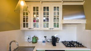 A kitchen with white cabinets, a gas stove, a kettle, and a sink. - Cabin Charm—Hot Tub Bliss Moments from the Beach (Cowes)
