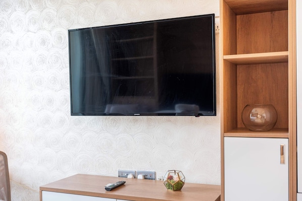 A flat-screen TV mounted on a wall with a patterned wallpaper. - Classy Studio in Al Barsha South that Sleeps 2 (Dubai)