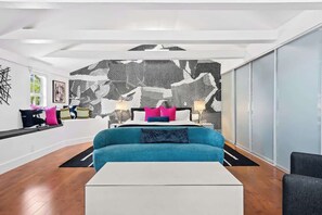 A modern room with a sofa, a white coffee table, and a patterned wall. - Vibrant Art-Filled Pool Gem near Beach & Las Olas! (Fort Lauderdale)
