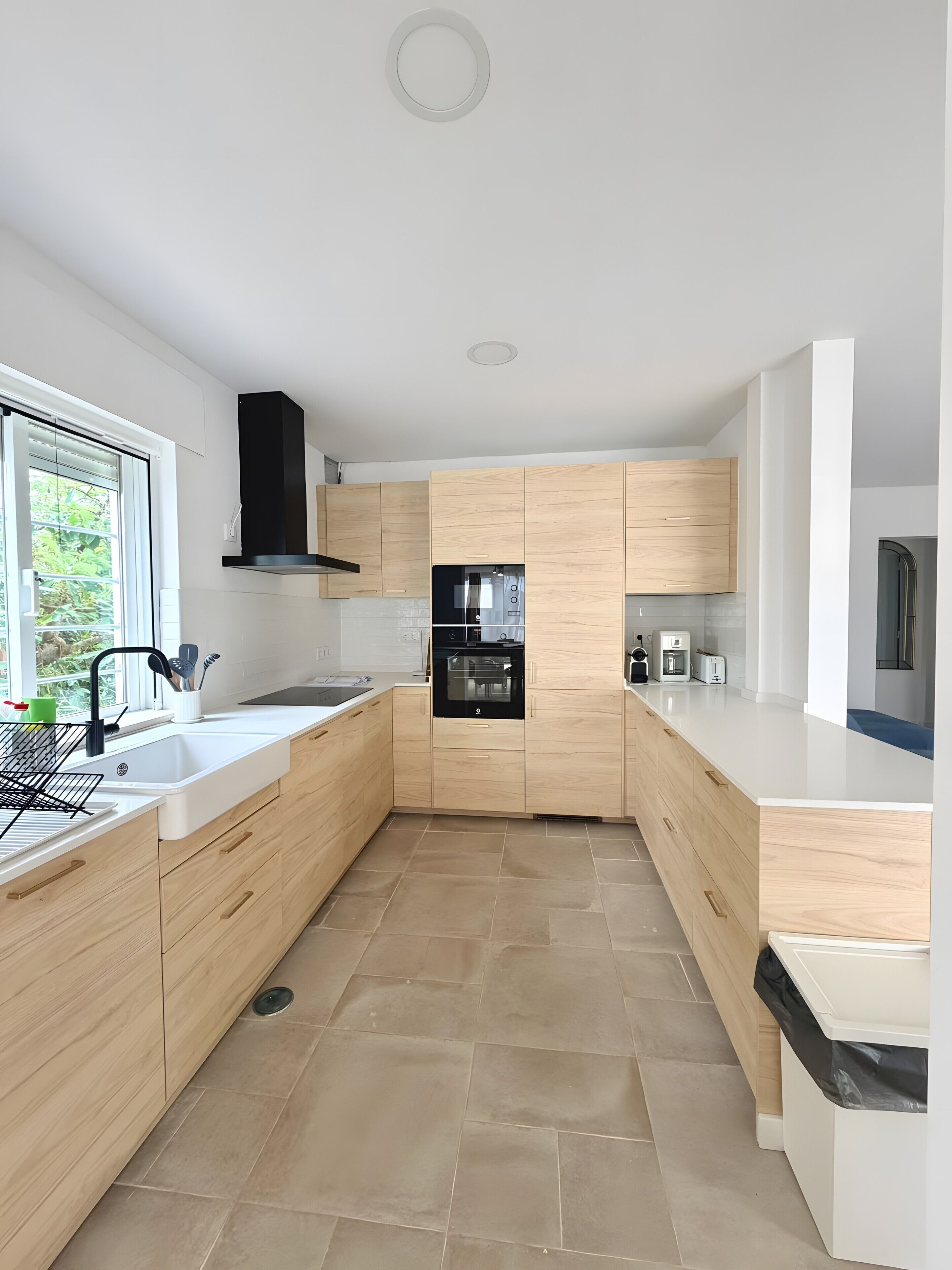 A modern kitchen with a central island, built-in oven, and a window providing natural light.