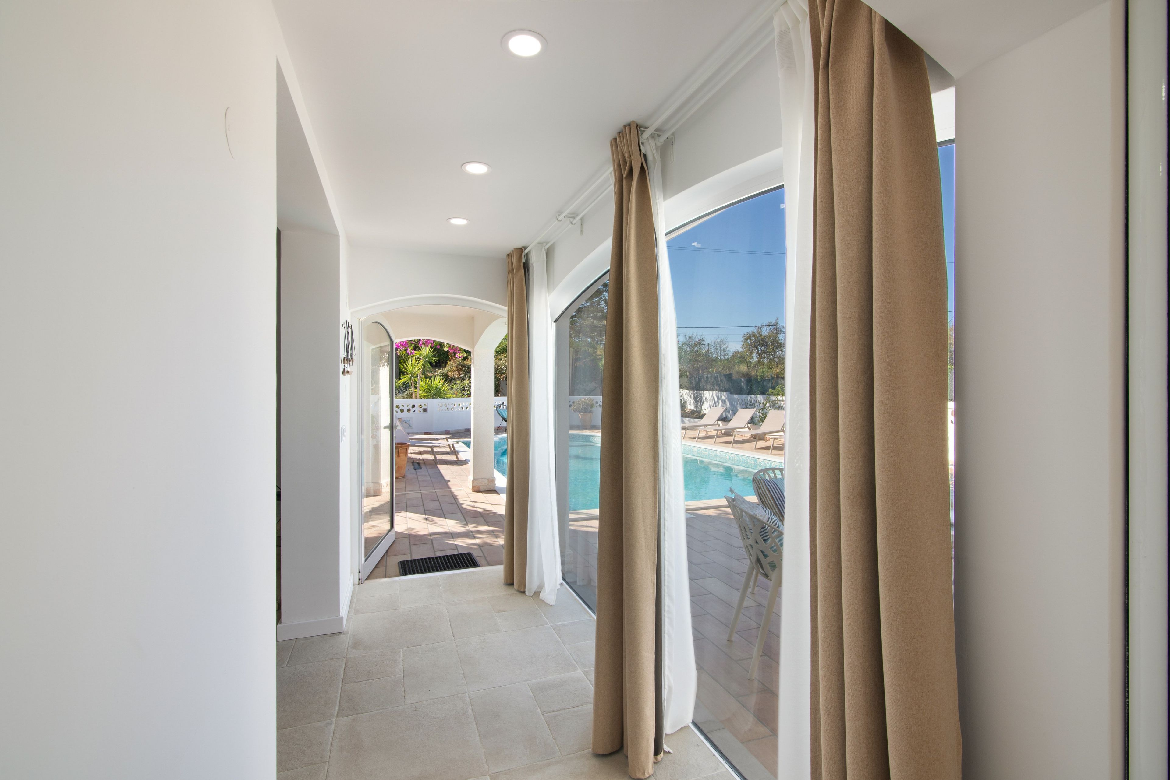 A corridor leading to a pool area with a view of the outdoors.
