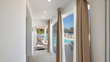 A corridor leading to a pool area with a view of the outdoors.