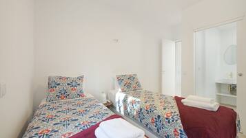 A twin room with two beds, a bathroom, and a door leading to another room.