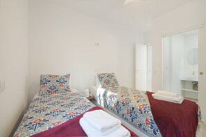Ein Doppelzimmer mit zwei Betten, einem Badezimmer und einer Tür zu einem weiteren Zimmer.