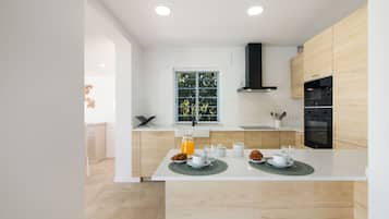 A modern kitchen with a central island, wooden cabinets, and a black range hood.