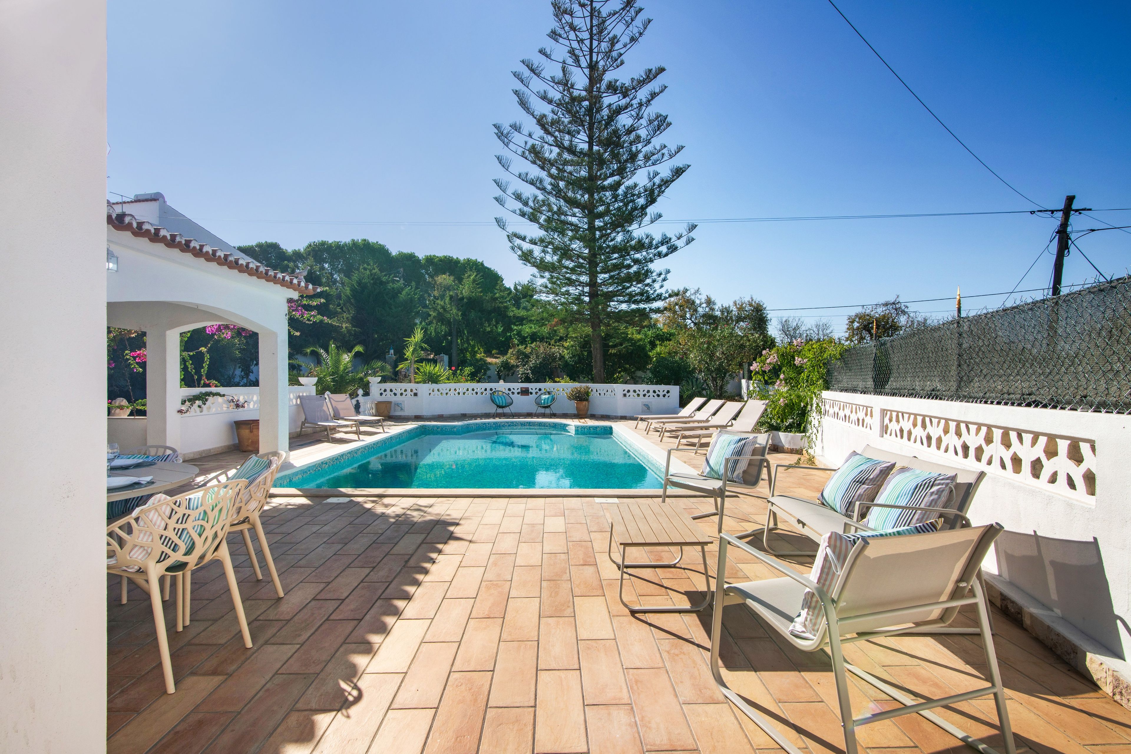 Une piscine avec des chaises longues et une pergola.