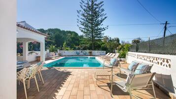 A swimming pool with lounge chairs and a pergola.