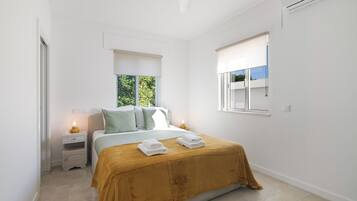 A bedroom with a bed, bedside tables, a window, and a ceiling fan.