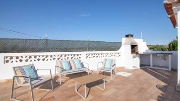 A terrace with a white wall, a metal fence, and a view of the sky.