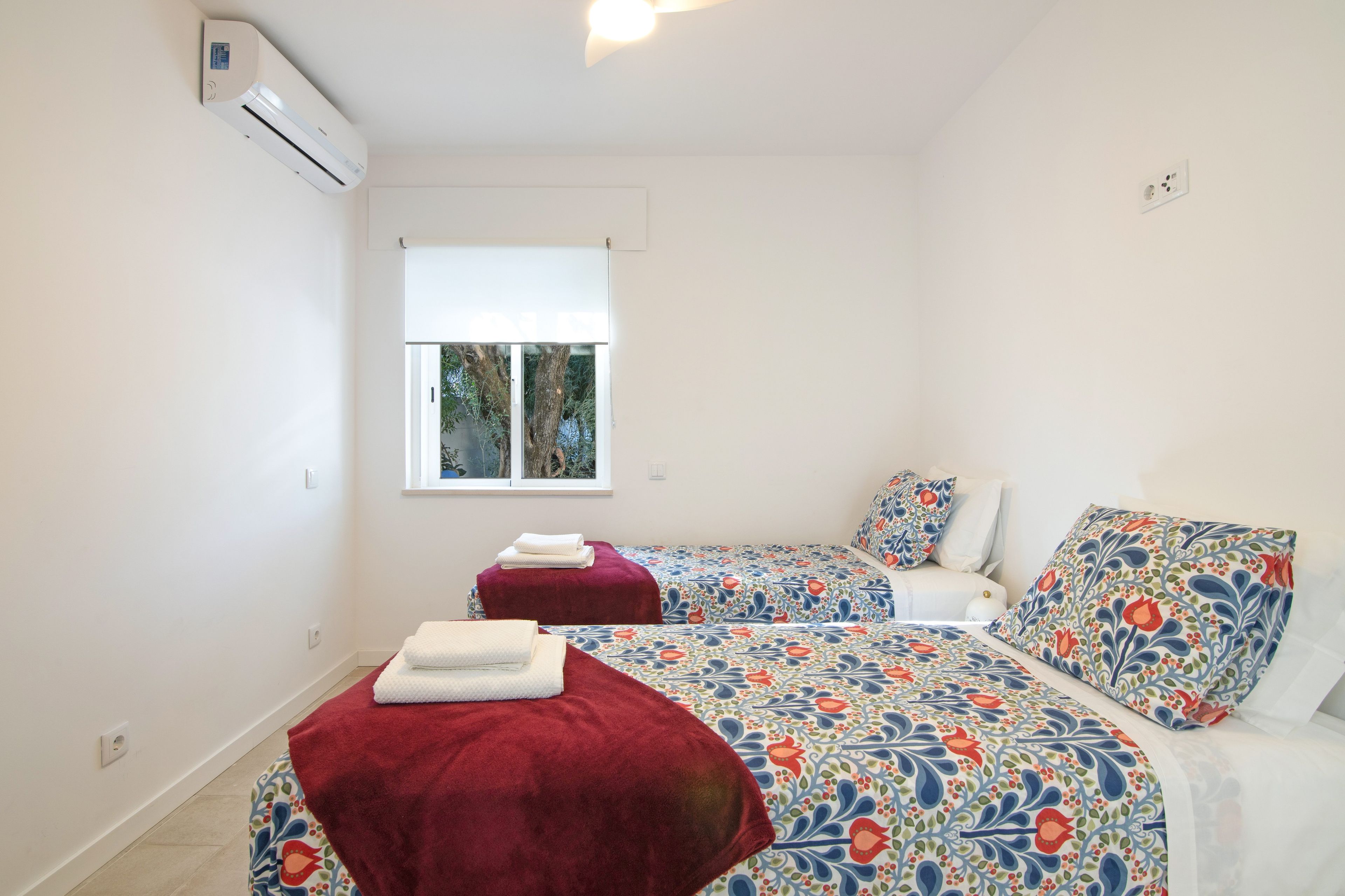 Une chambre avec deux lits, une fenêtre et un appareil de climatisation.