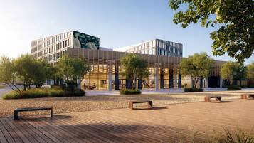 Un bâtiment moderne doté d’une terrasse en bois et d’espaces aménagés pour s’asseoir.