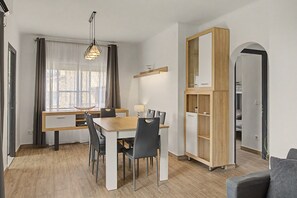 Ein stilvoller Essbereich mit Holztisch und -stühlen, einer Pendelleuchte und Blick ins Freie durch große Fenster.