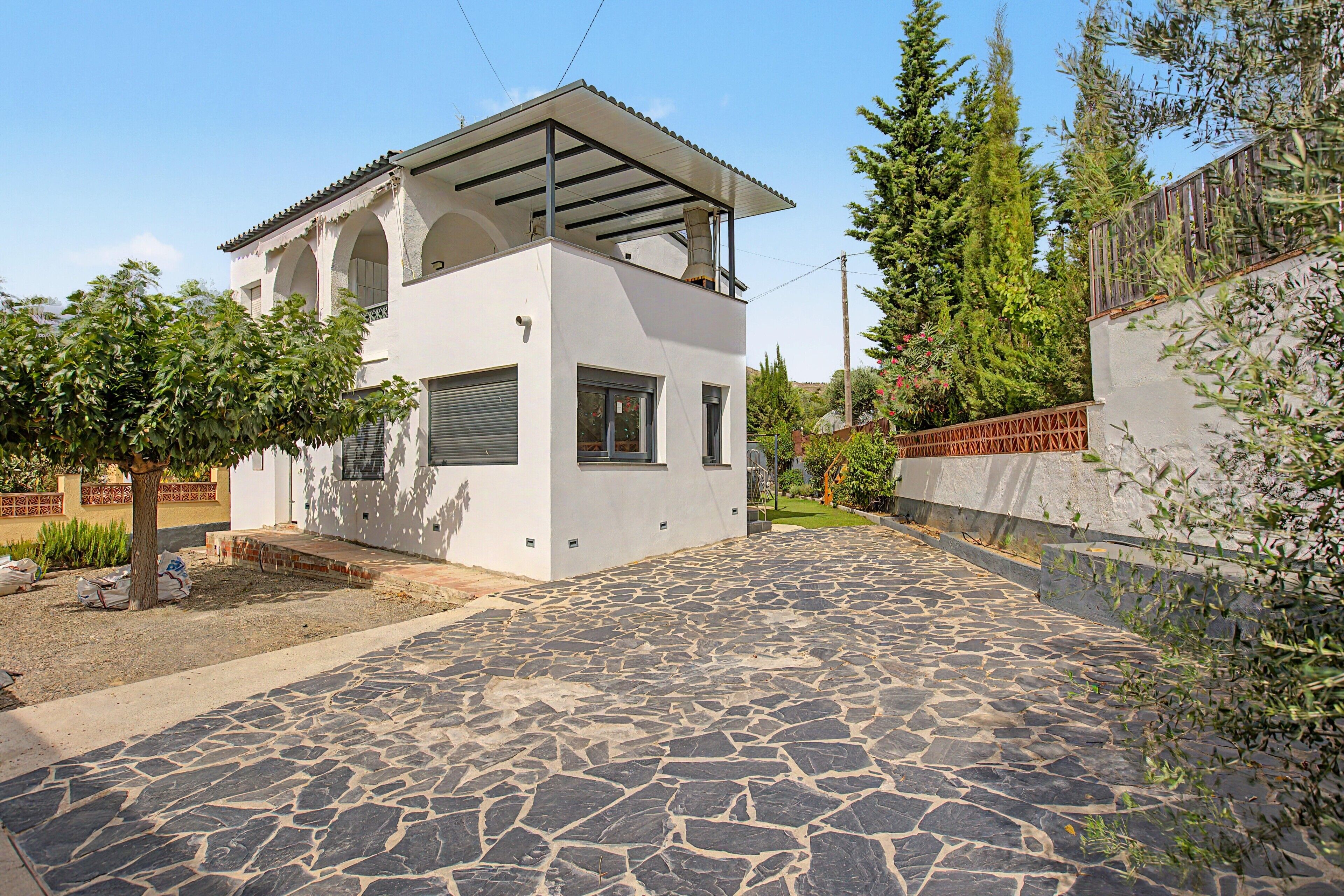 A modern two-story house with a stone-paved driveway and a garden area.