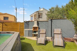 Ein Garten mit Schwimmbad, zwei Liegestühlen, einem Grill und einem kleinen Geräteschuppen.
